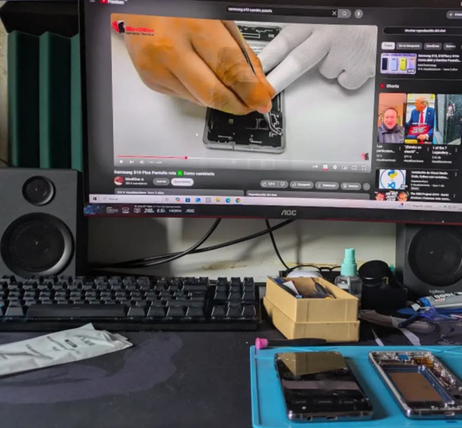 Mesa de casa con un Samsung Galaxy S10 abierto y un tutorial de cambio de pantalla en el monitor